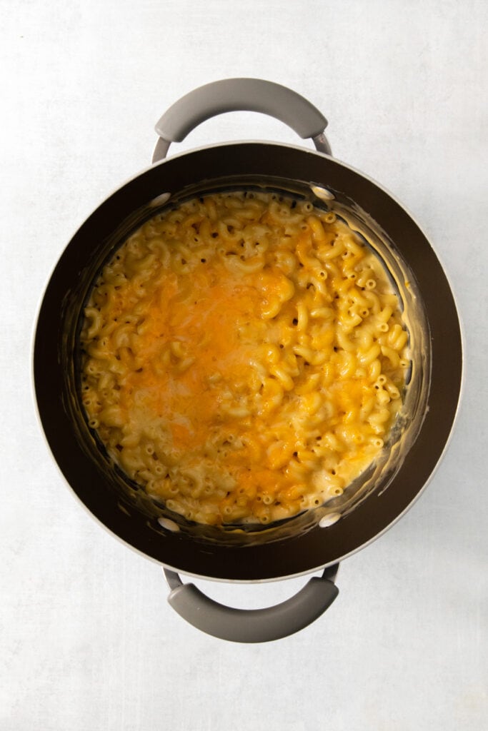 Macaroni and cheese in a pot on a white surface.