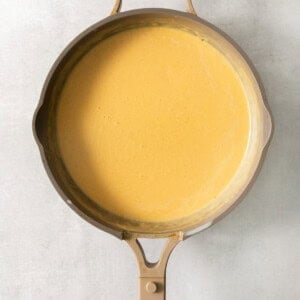 A frying pan filled with a yellow sauce.