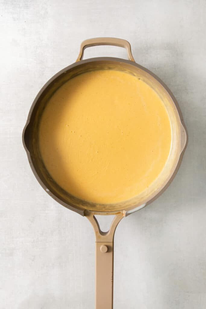 A frying pan filled with a yellow sauce.