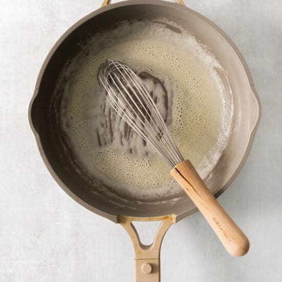 A frying pan with a whisk in it.