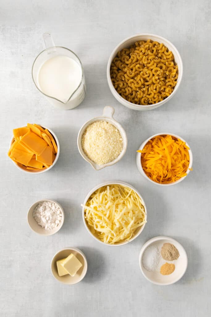 A bowl of pasta, cheese, milk and other ingredients on a gray background.