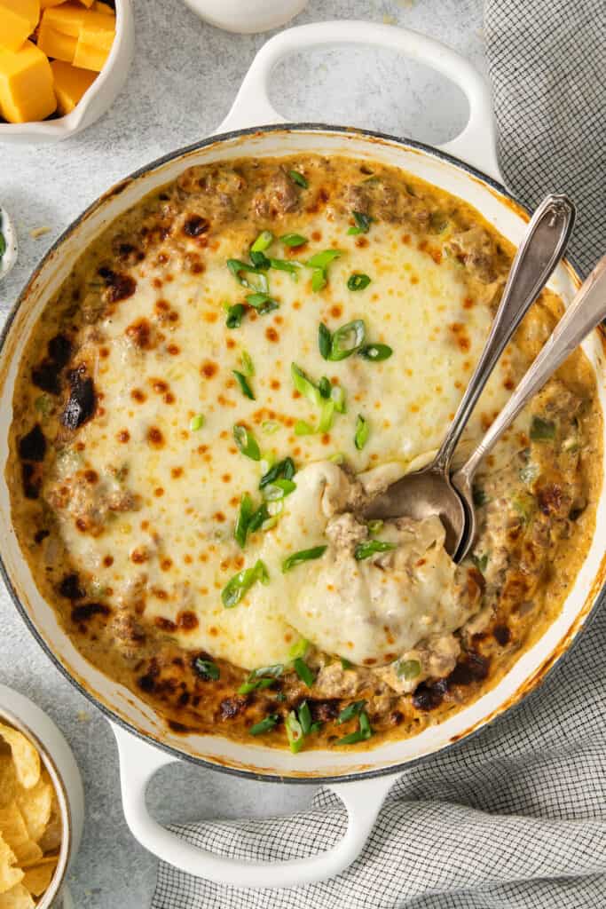 Cheesy meatball dip in a white dish with a spoon.