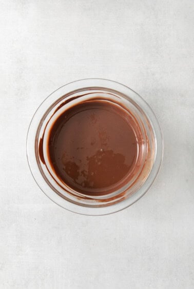 Chocolate sauce in a glass bowl on a white background.