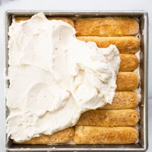 A pan filled with cinnamon rolls and whipped cream.