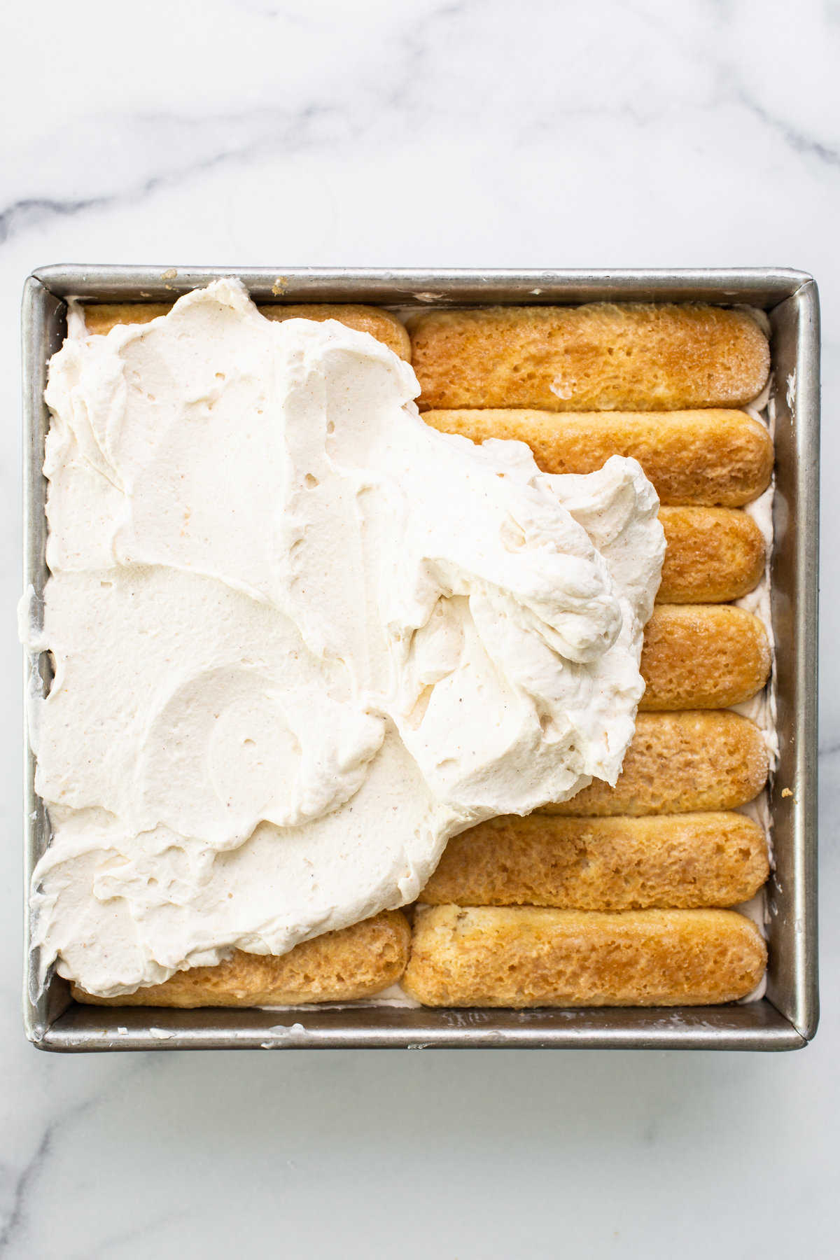 A pan filled with cinnamon rolls and whipped cream.