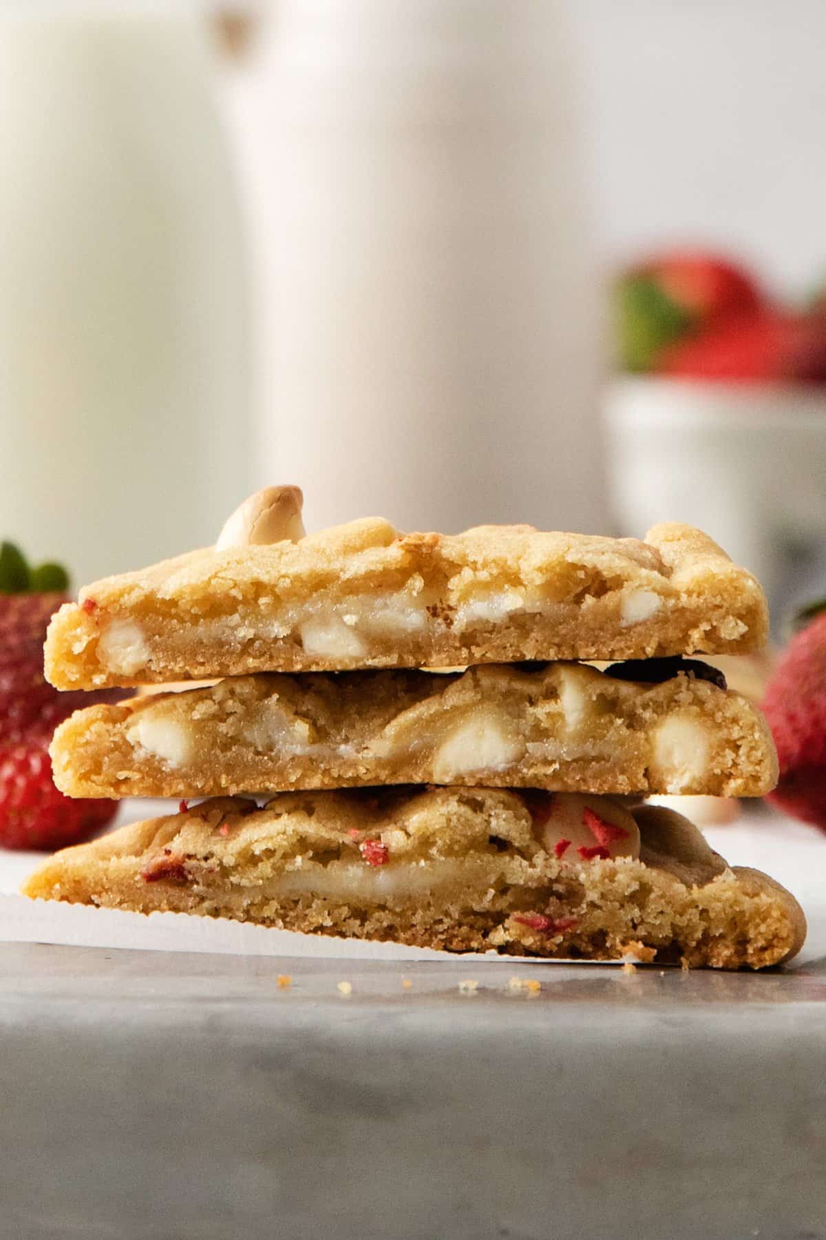 A stack of cookies with strawberries next to a glass of milk.