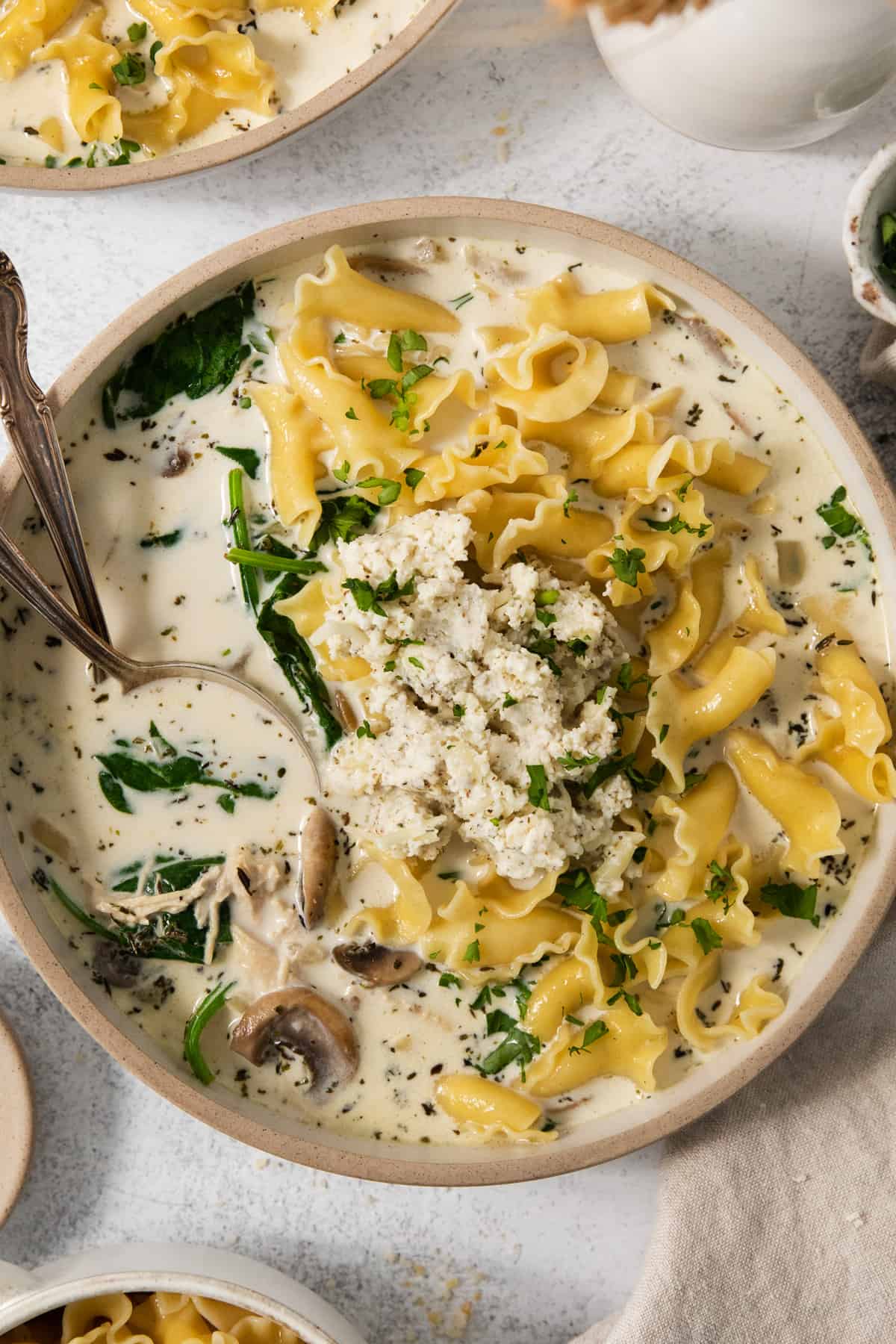 A bowl of mushroom and spinach soup with a spoon.