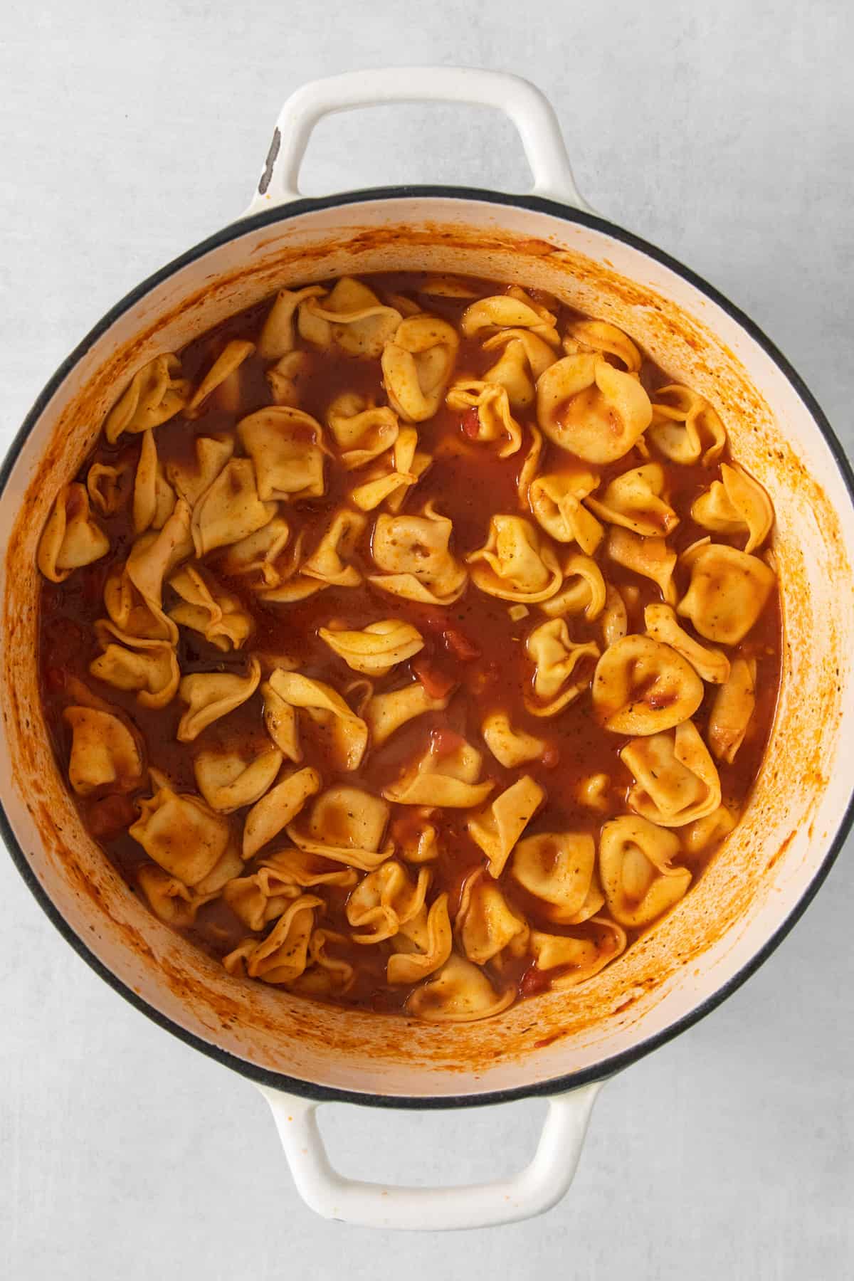 A pot of cooked tortellini pasta in tomato sauce.