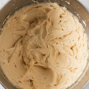 A metal bowl filled with creamy, beige-colored cookie dough for making egg-free chocolate chip cookies.