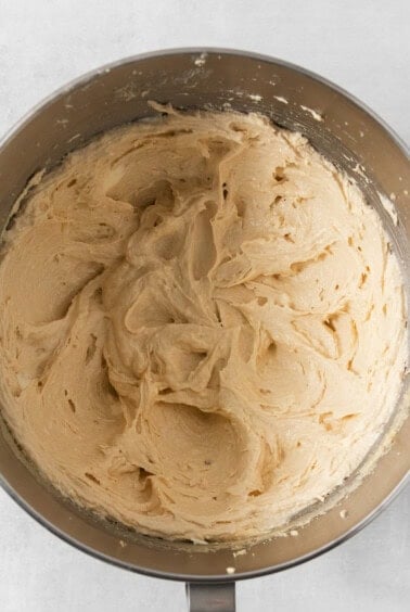 A metal bowl filled with creamy, beige-colored cookie dough for making egg-free chocolate chip cookies.
