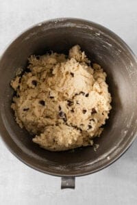 A bowl of egg-free chocolate chip cookie dough sits invitingly on a light-colored surface.