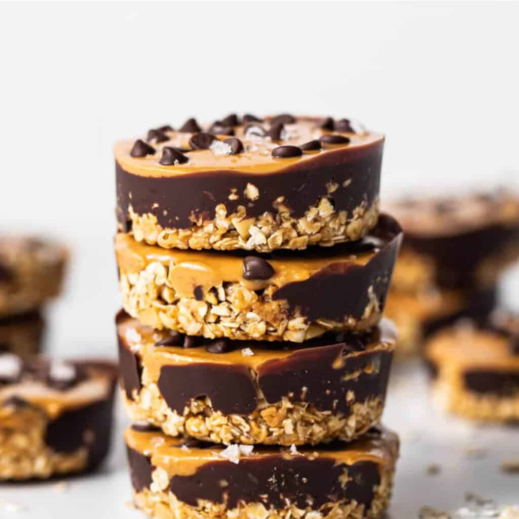 A stack of four no-bake peanut butter chocolate oat bars with a visible layer of chocolate chips on top.