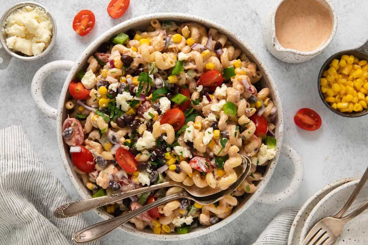 Add a flavorful twist to a traditional pasta salad with this scrumptious Mexican pasta salad! Full of Mexican flavors, this great side dish was meant to impress. Mexican pasta salad in a bowl with 2 spoons.