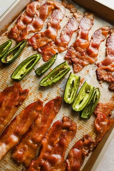 Crispy baked bacon and roasted jalape&ntilde;os on a parchment-lined sheet pan