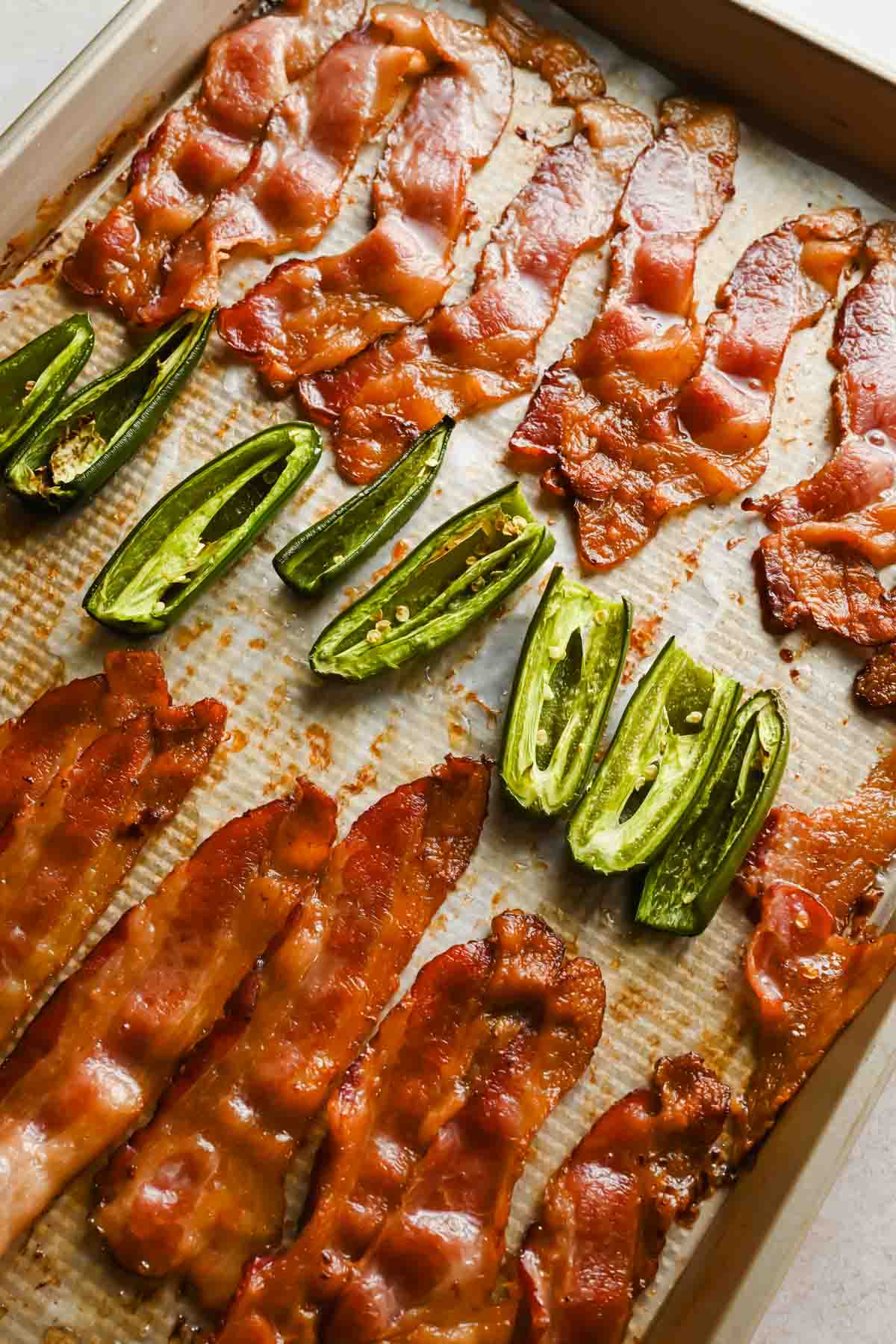 Crispy baked bacon and roasted jalape&ntilde;os on a parchment-lined sheet pan