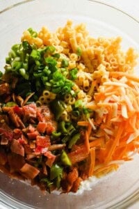 Bowl of ditalini, green onions, cheddar, and bacon mixture before tossing