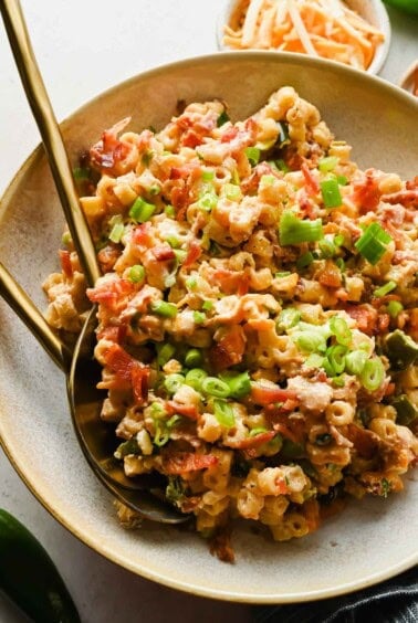 Jalape&ntilde;o popper pasta salad with crispy bacon, green onions, and cheddar cheese served with gold utensils