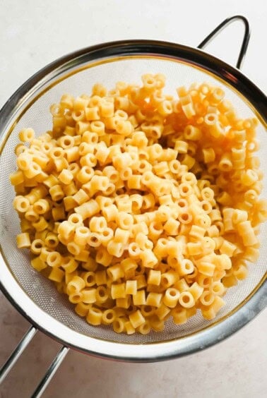 Cooked ditalini pasta draining in a mesh strainer