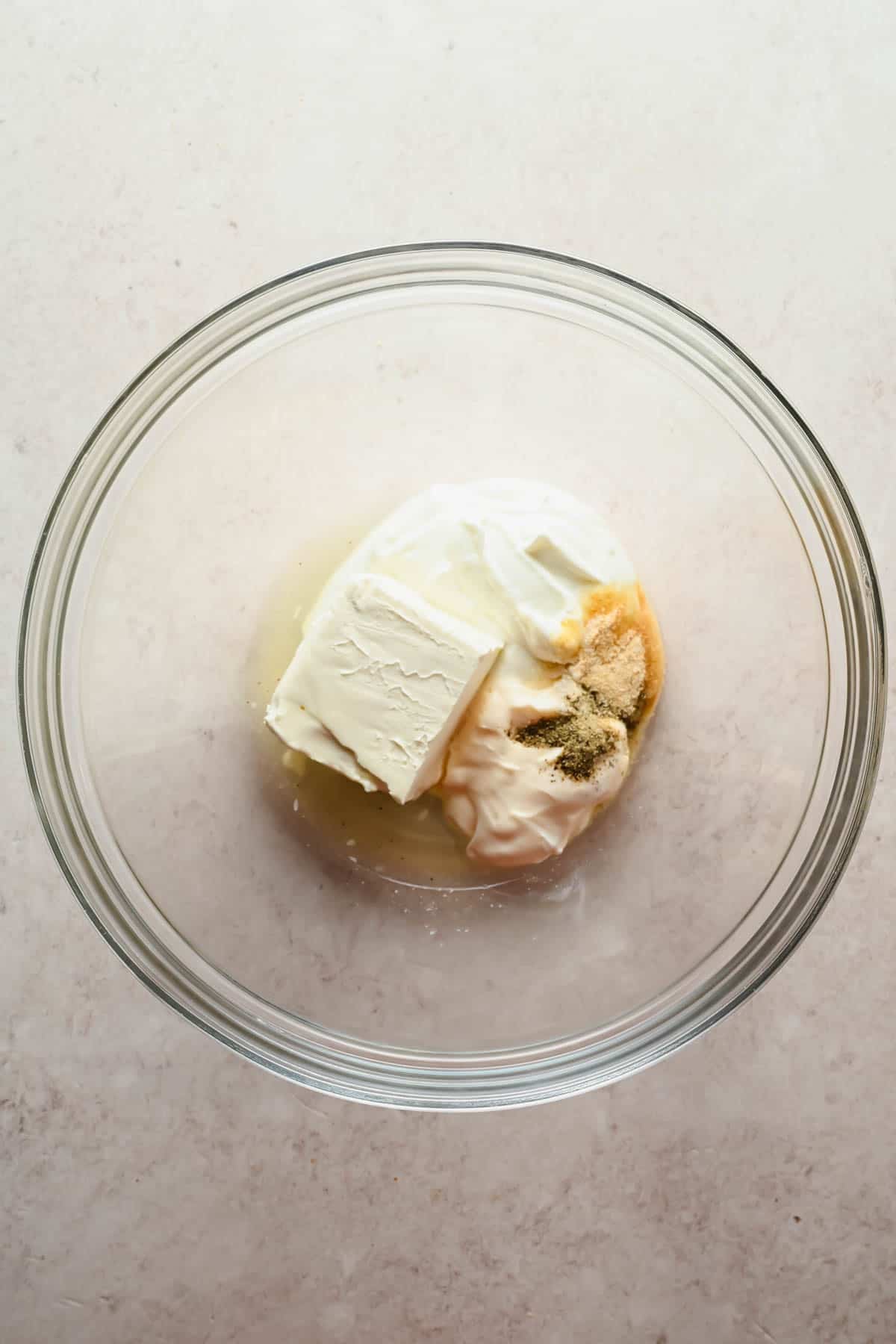 Cream cheese, mayo, sour cream, lemon juice, and seasonings in a glass bowl for jalape&ntilde;o popper dressing