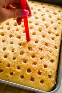 Using a straw to poke evenly spaced holes into a baked vanilla cake