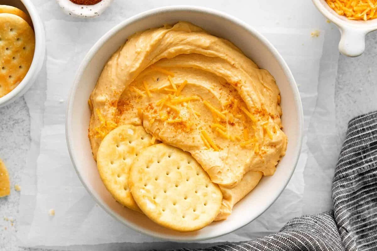 This 6-ingredient homemade spreadable cheese comes together in 15 minutes flat. You'll absolutely love the creamy texture and flavor. Homemade spreadable cheese in a bowl with crackers.