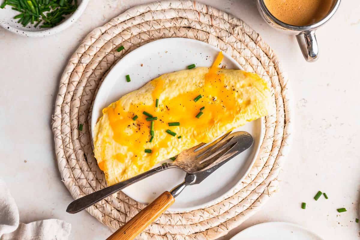 Cheese omelette on a plate topped with fresh chives.