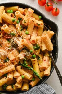 Finished spicy cottage cheese pasta with rigatoni, tomatoes, peas, Parmesan, and basil
