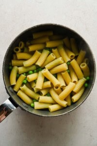 Cooked rigatoni and green peas in a pot