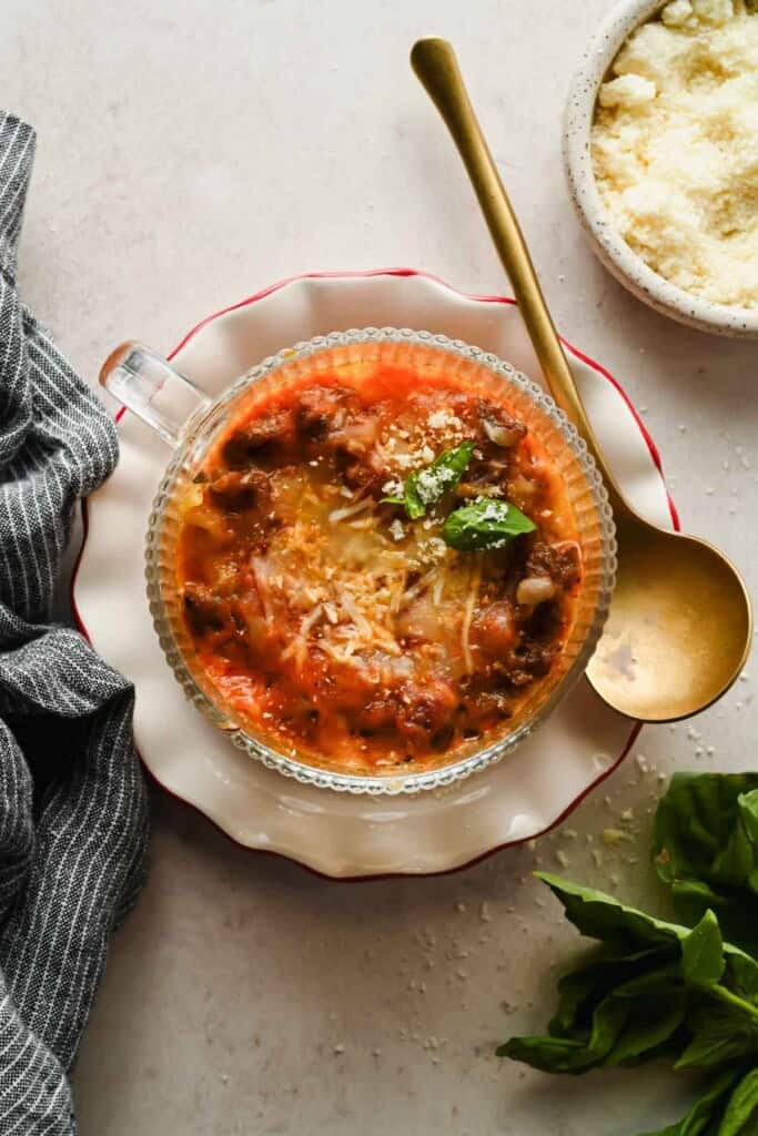 Overhead view of finished microwave lasagna in a mug topped with melted cheese and basil