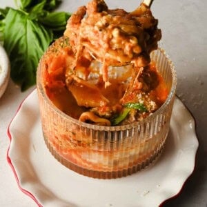 Fork pulling up a cheesy bite of microwave lasagna from a mug