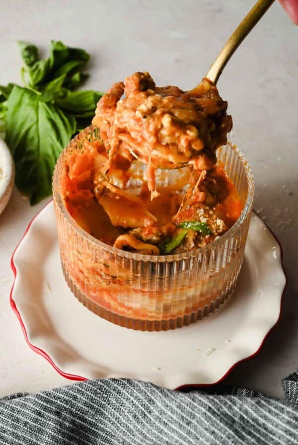Fork pulling up a cheesy bite of microwave lasagna from a mug