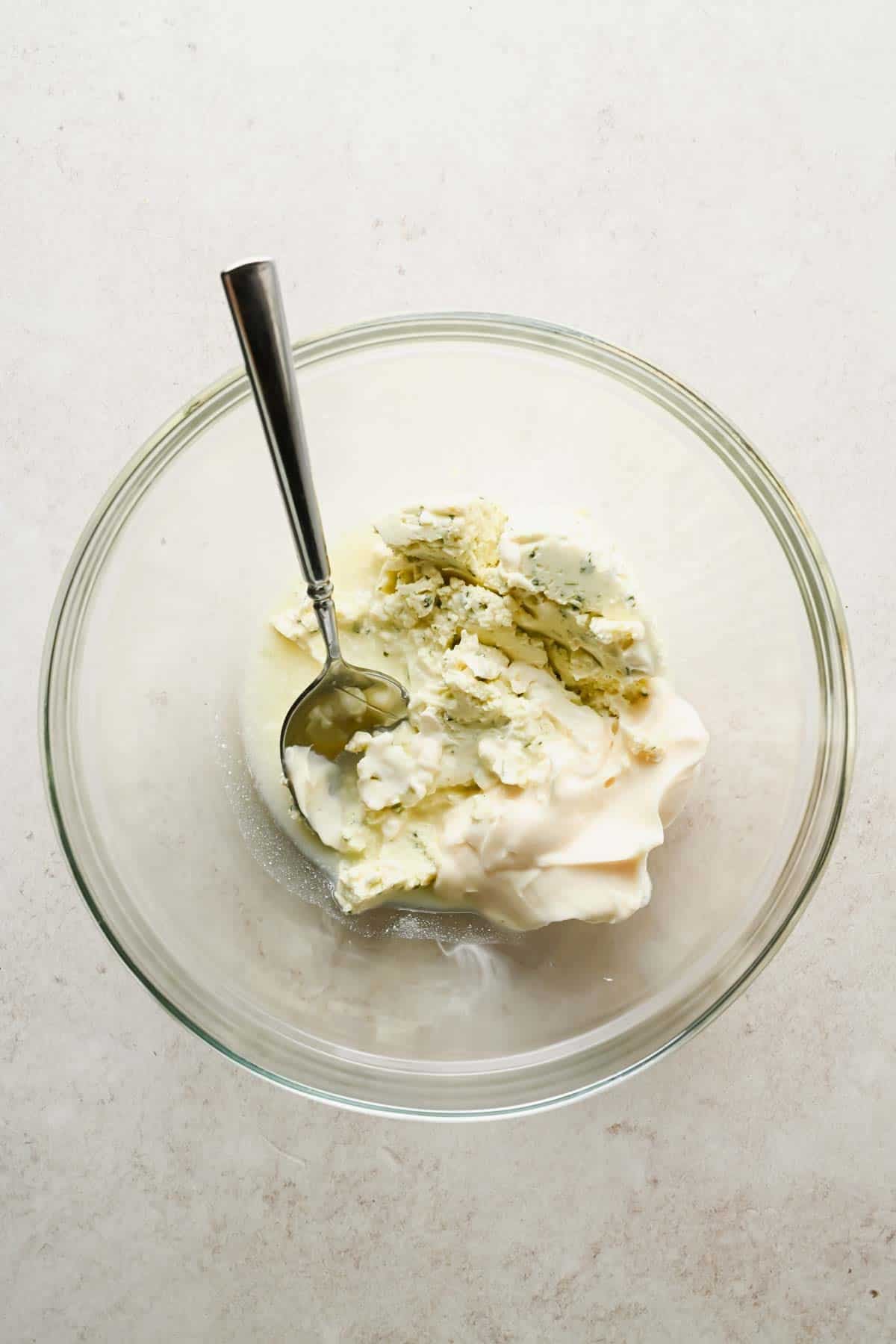 Boursin cheese, mayonnaise, and lemon juice in a clear mixing bowl before whisking.