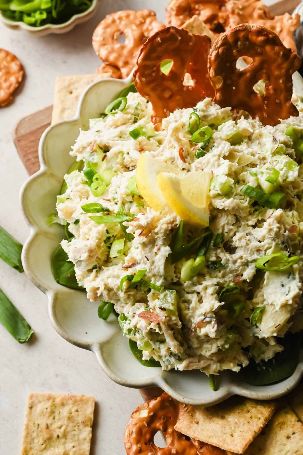 Spoonful of creamy Boursin chicken salad lifted from a serving bowl with celery and green onions.