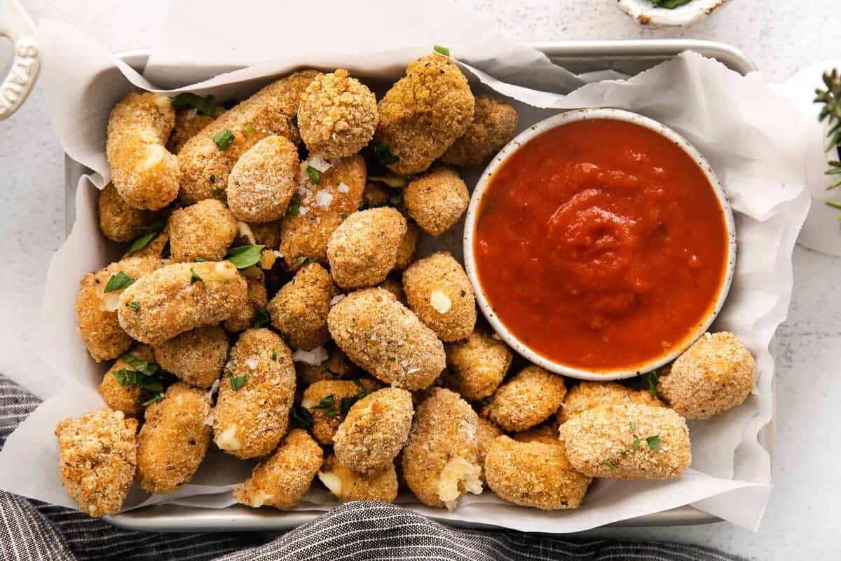 Air fryer cheese curds in a basket with marinara sauce