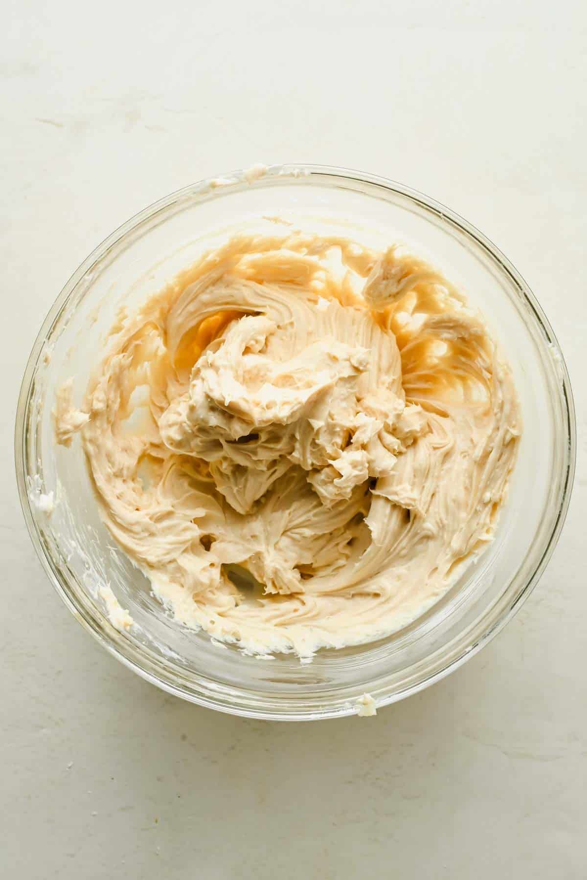 Cream cheese filling mixed with brown sugar and vanilla in a glass bowl