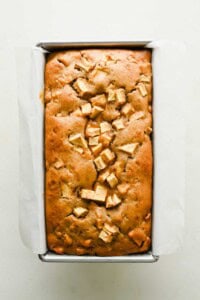 Freshly baked apple fritter bread in a parchment-lined loaf pan