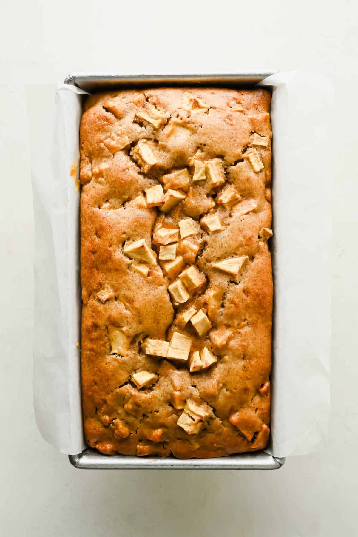 Freshly baked apple fritter bread in a parchment-lined loaf pan