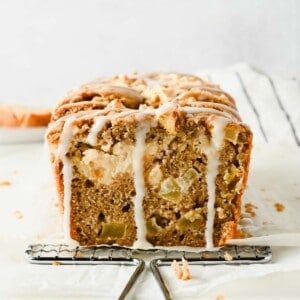 Sliced cream cheese apple fritter bread showing diced apples, glaze, and a cream cheese stripe