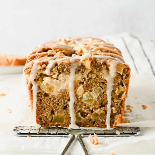 Sliced cream cheese apple fritter bread showing diced apples, glaze, and a cream cheese stripe