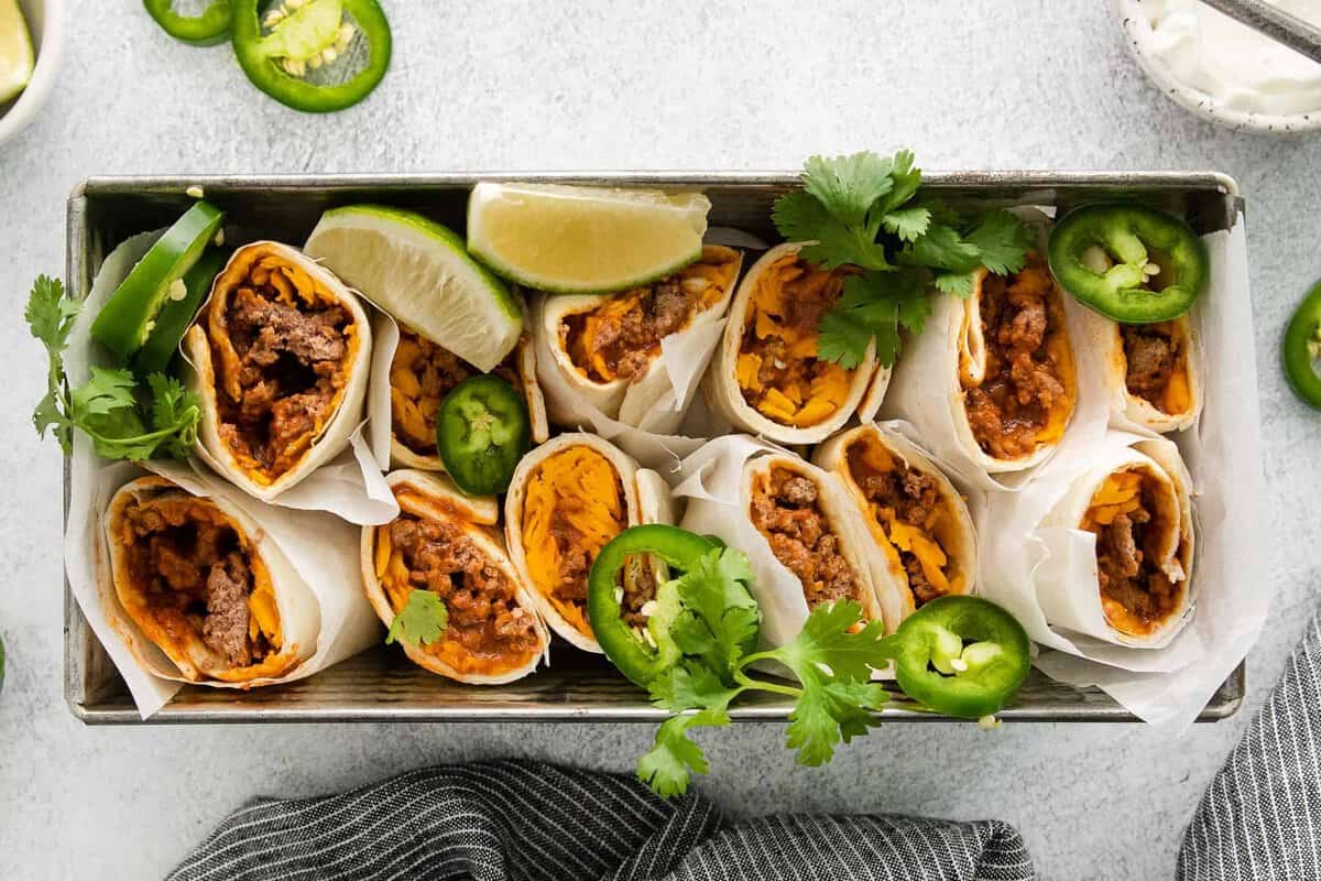 This Taco Bell Chili Cheese Burrito dupe recipe tastes exactly like the real deal. You only need 6 ingredients and 25 minutes! burritos in dish sliced I half with cilantro.