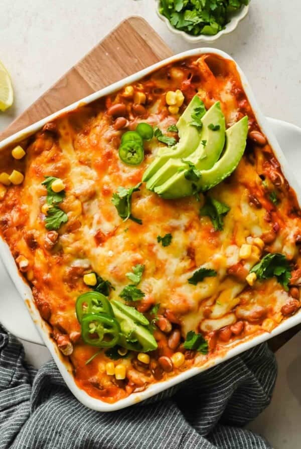 Bubbly cheese-topped tortilla bake with avocado, jalapeño slices, and cilantro, seen at an angle.
