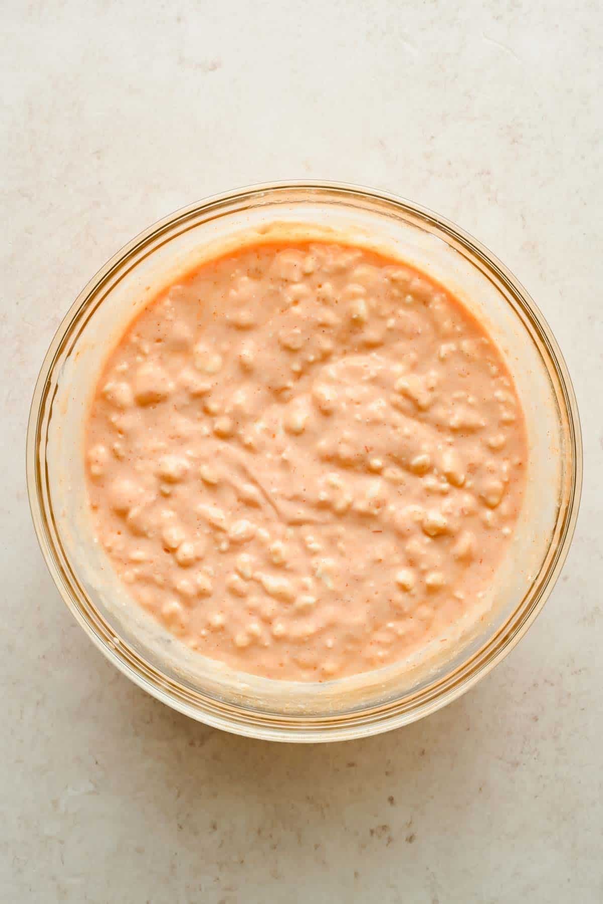 A bowl of pink-orange enchilada sauce mixed with visibly textured cottage cheese.