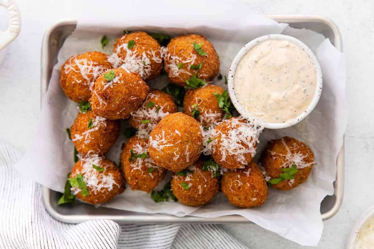 Got leftover risotto? Make Parmesan Arancini - a delicious fried rice ball appetizer! Arancini next to ranch dipping sauce.