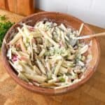 Apple celery salad with dates and walnuts in creamy Boursin dressing in a wooden bowl.
