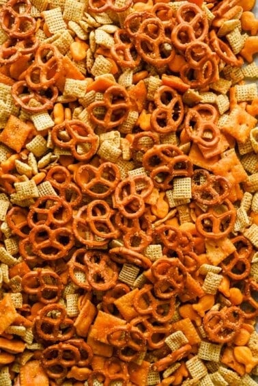 Close-up of golden cheesy Chex mix with Rice Chex, pretzels, Cheez-Its, and Goldfish.