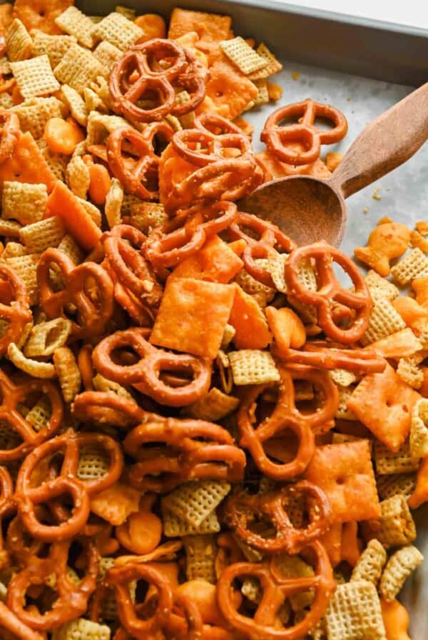 A bowl of finished cheesy Chex mix with pretzels and cheese crackers, ready to serve.