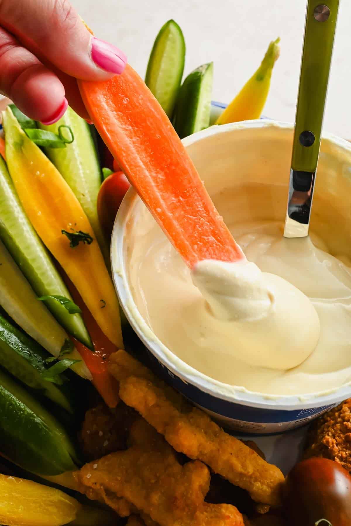 A carrot dipped into creamy cottage cheese honey mustard sauce.