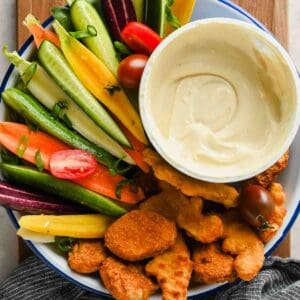 Creamy honey mustard dip in a bowl with chicken nuggets and colorful vegetables.