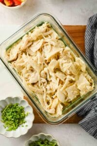 Microwave chicken enchilada with melted Monterey Jack cheese in a glass container.